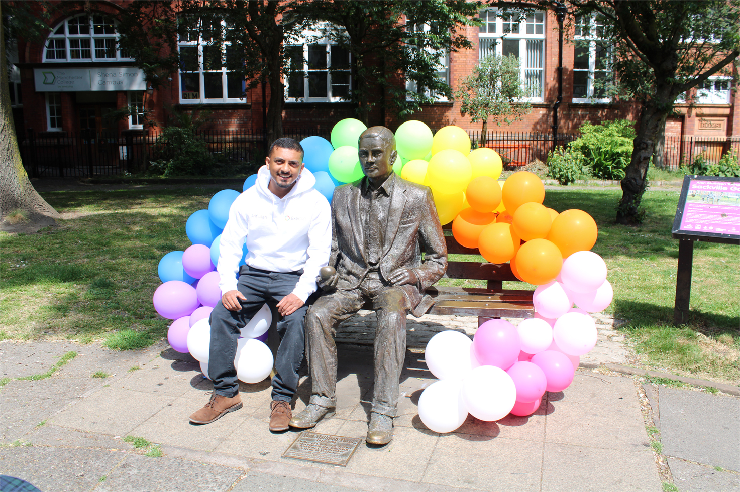 Our completed arch of balloons colour coordinated with the colours of the rainbow wrapped around Alan Turing's bench, pictured with Arif.