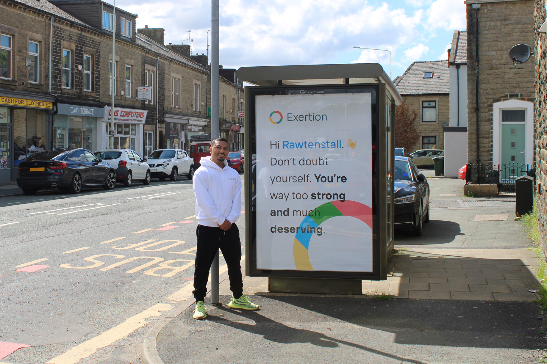 A bus shelter on Bacup Road, Rawtenstall displaying our advertisement (pictured with Arif).
